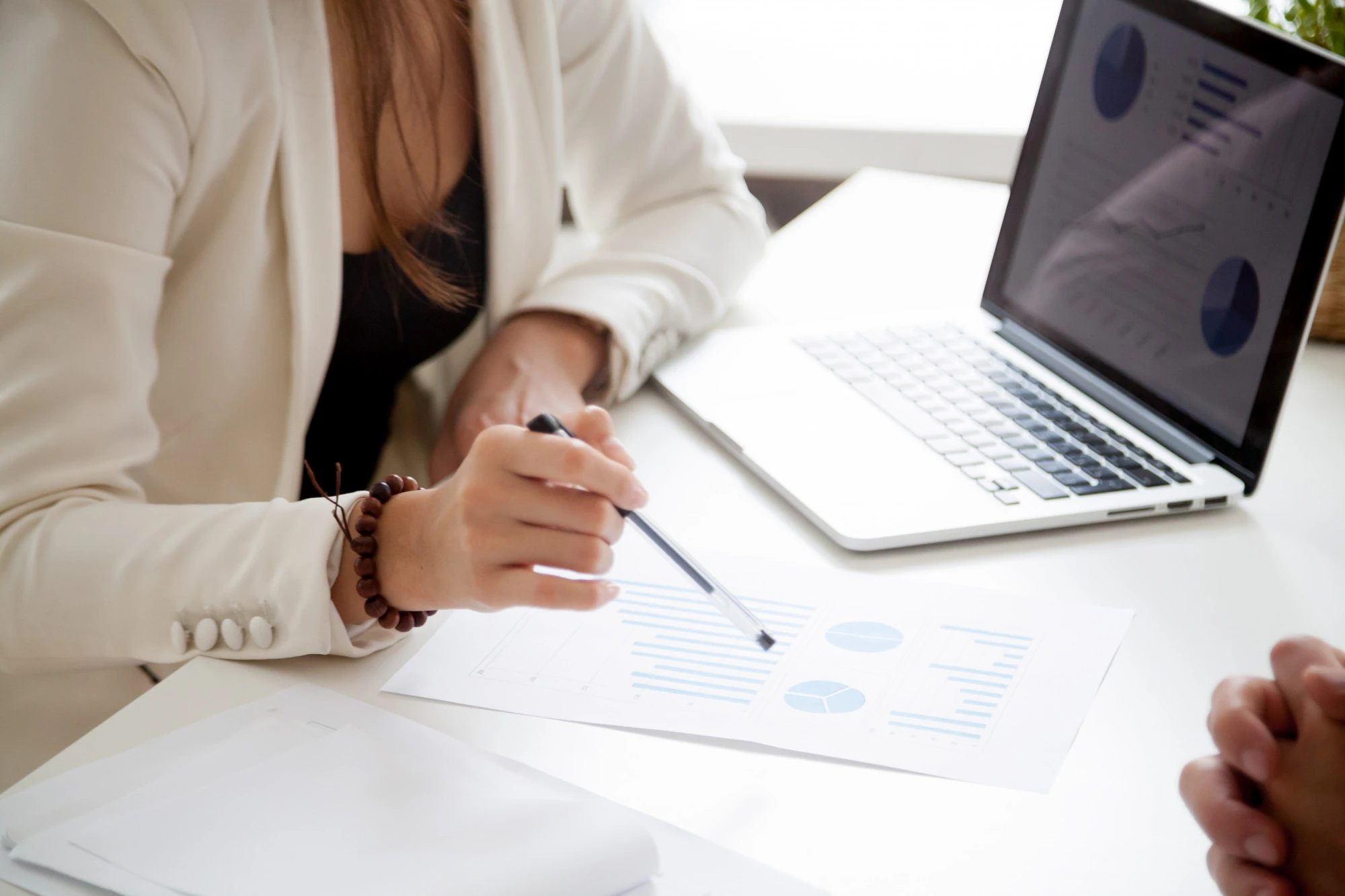 Consultora analiza gráficos de resultados comerciales junto a un portátil