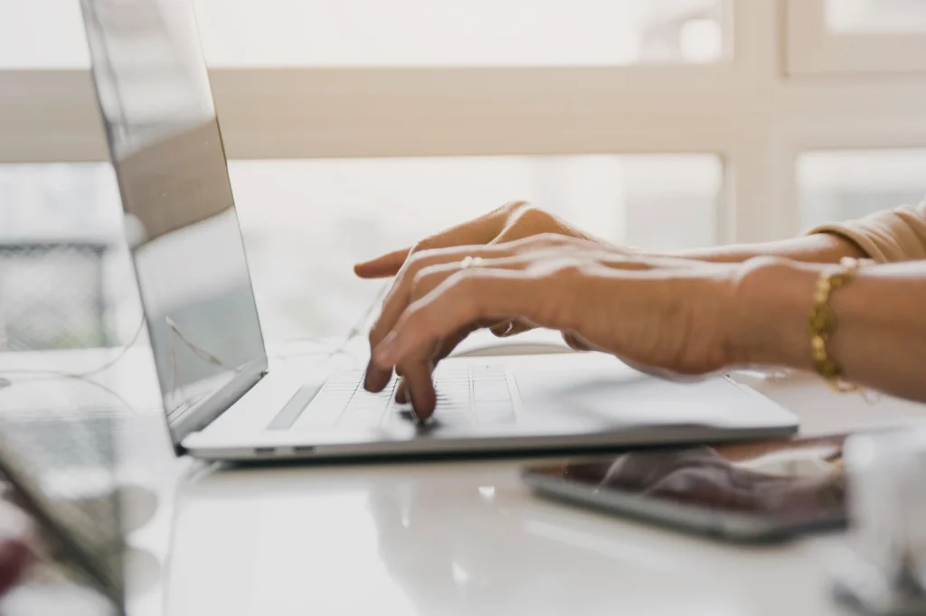 Manos de una profesional escribiendo en un portátil sobre la mesa de trabajo